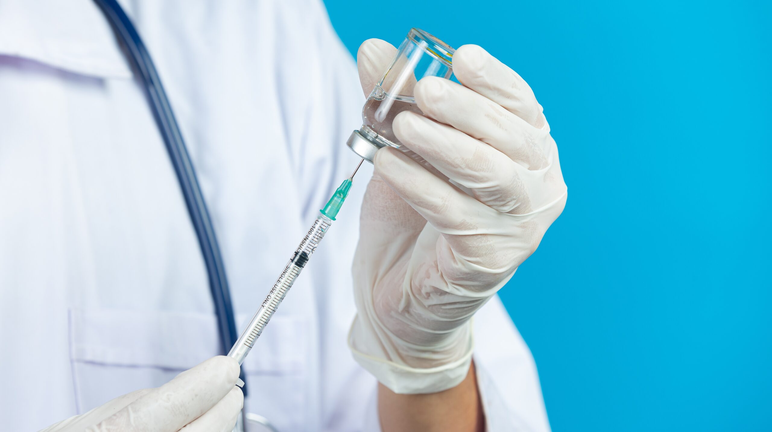 close up picture of docter’s  hands holding hypodermic syringe